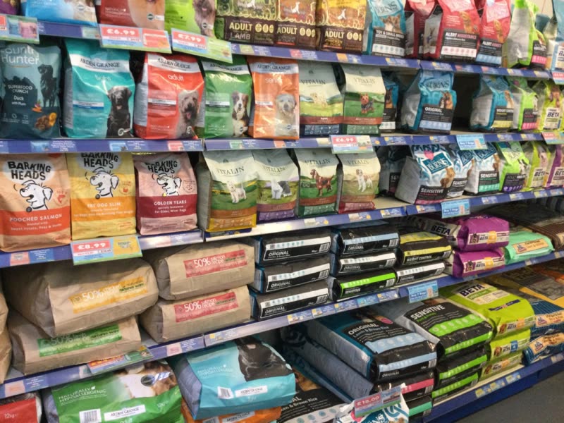 A shop aisle lined with shelves of bagged and boxed pet food